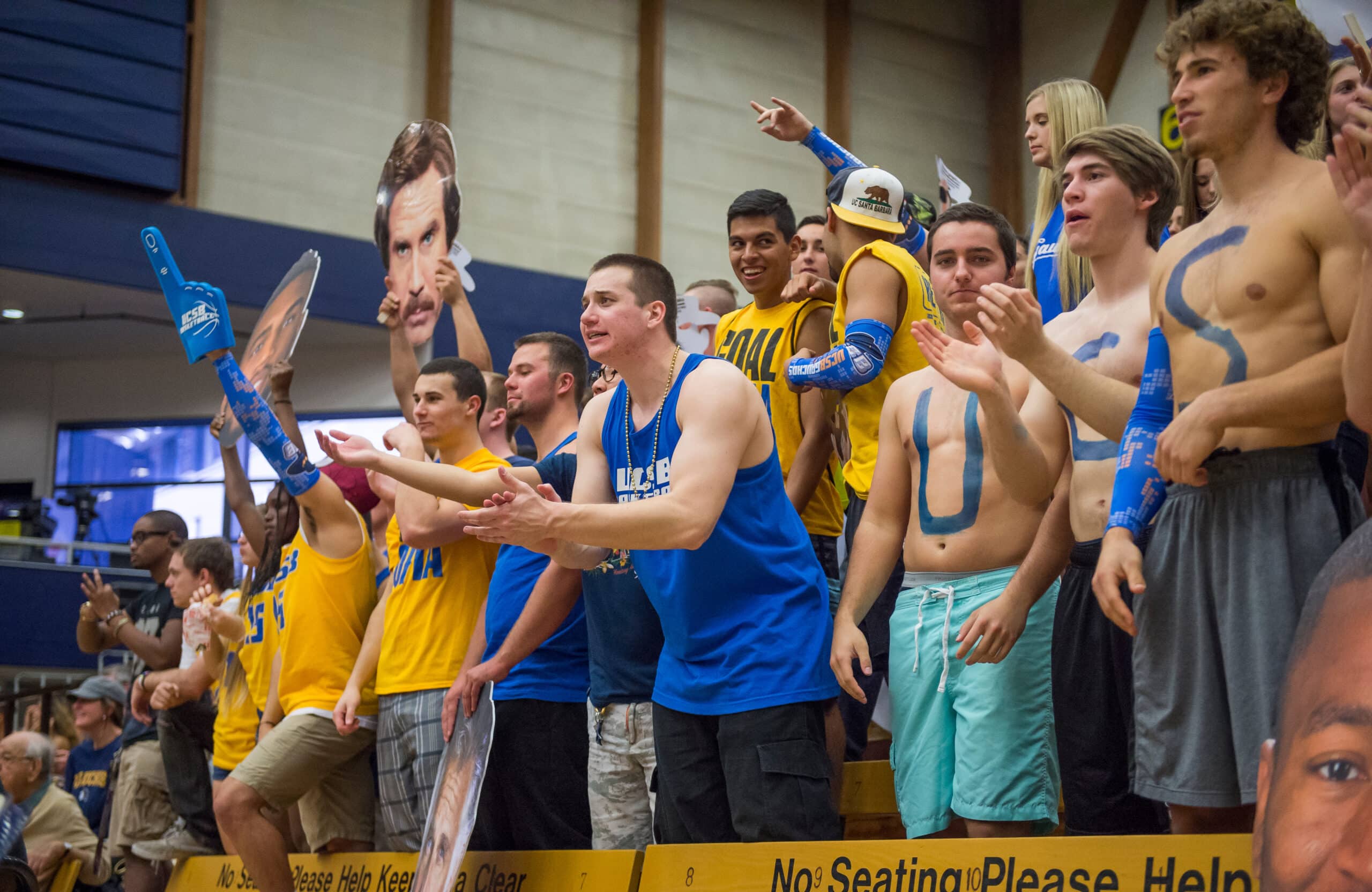 UCSB Surge student section rallying behind the basketball team, decked out in yellow and blue.