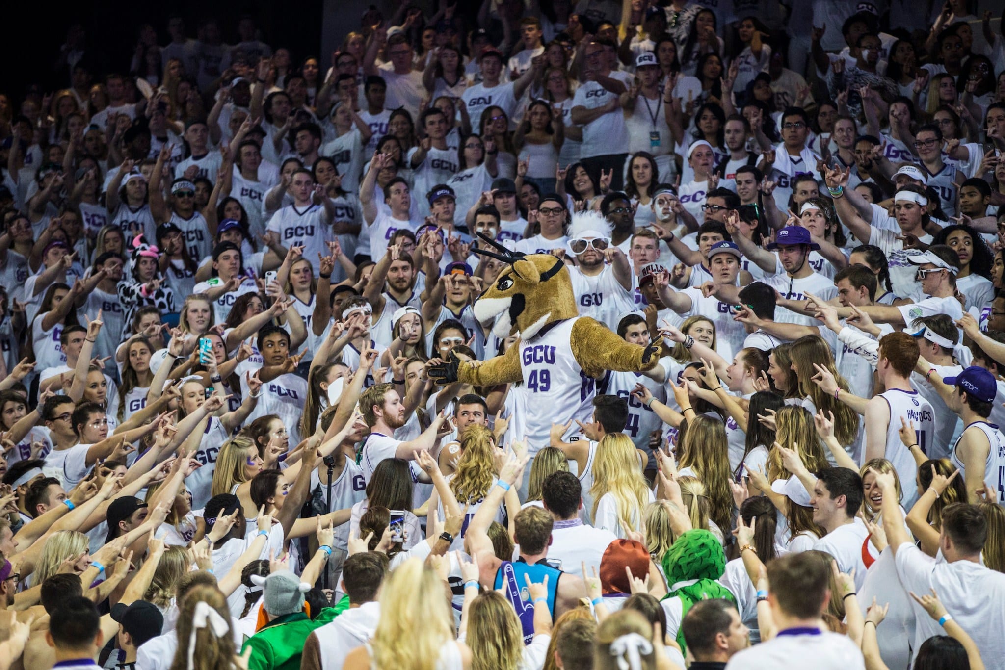 GCU student section packed at a basketball game, fans surrounding the school mascot in the stands, creating an exciting and spirited atmosphere.