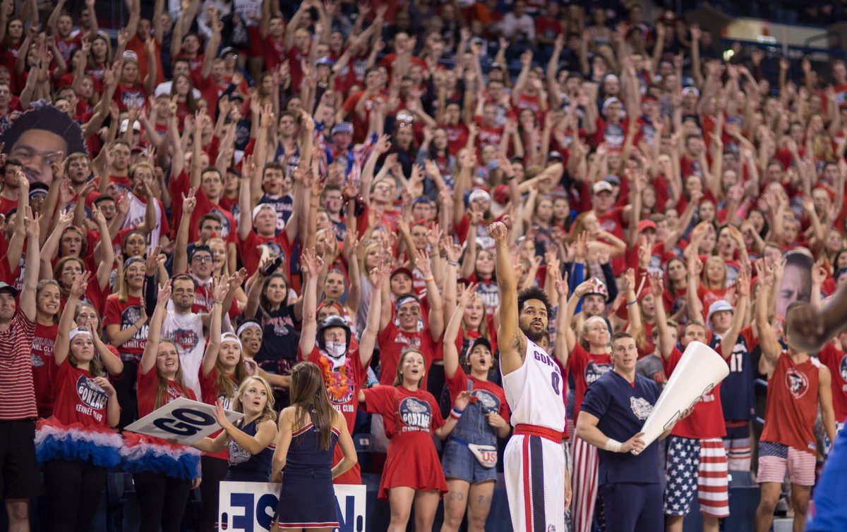 Gonzaga Student Section with hands raised in anticipation as a basketball player takes his shot, showcasing their enthusiastic support for the team.