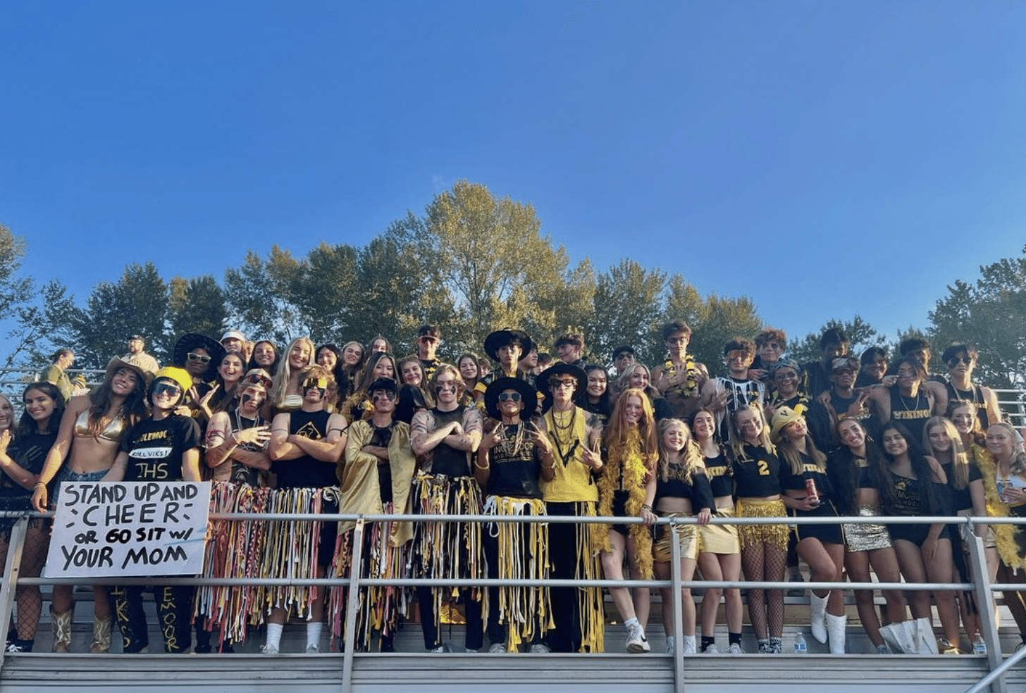 Inglemoor High School student section, wearing gold and black gear, standing together in the bleachers, showing their school pride and unity.